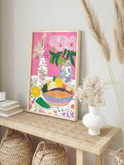 Colourful still life illustration of salmon, lemons, olives, asparagus, and pink flowers in, in an alternate framed mockup