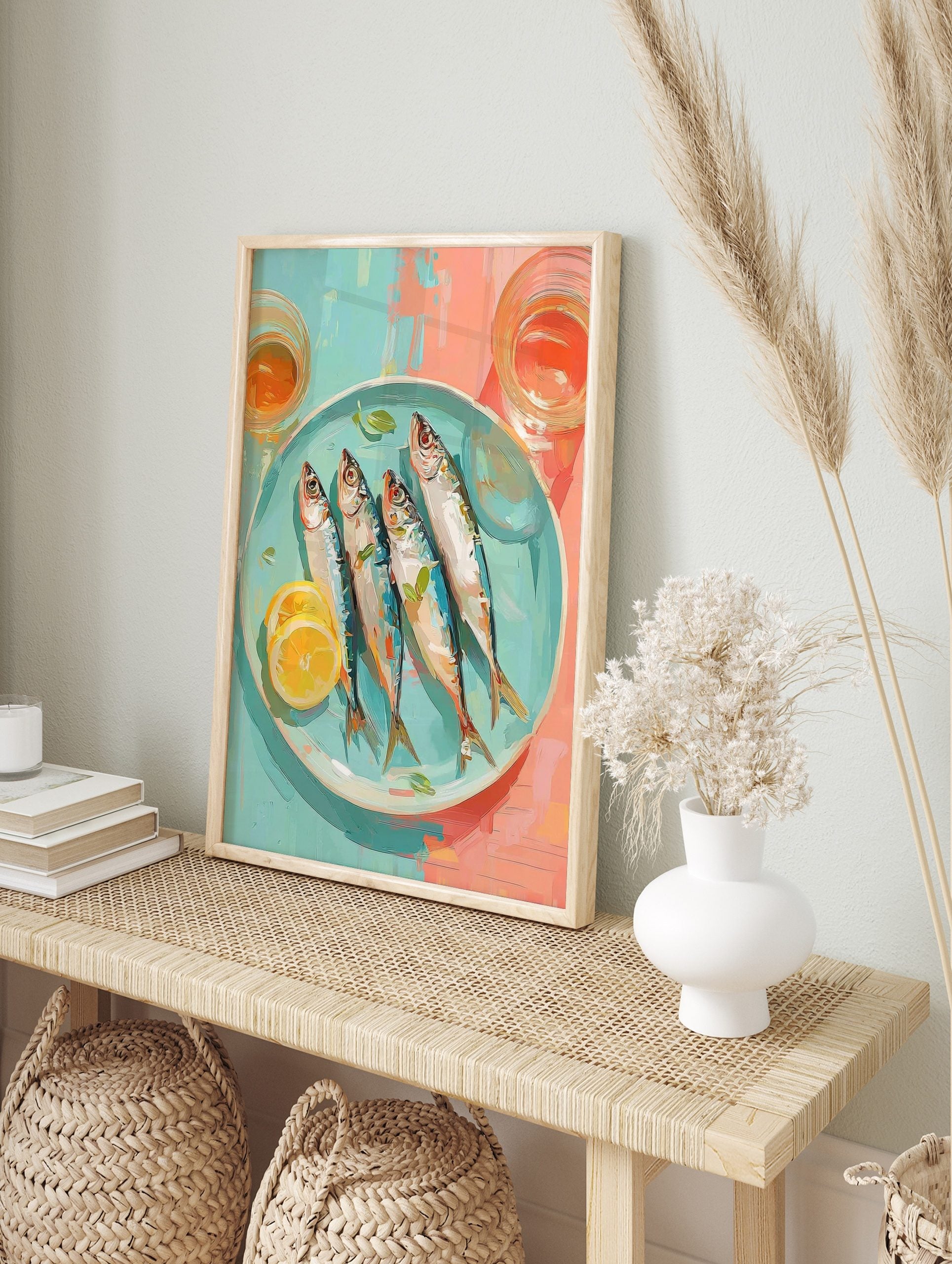 Illustrative wall art of four whole sardines with lemon and herbs on a blue plate, with, in an alternate framed mockup