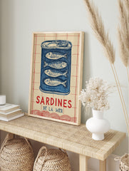 Illustrative blue sardine tin wall art with four fish and 'SARDINES DE LA MER' text on a, in an alternate framed mockup