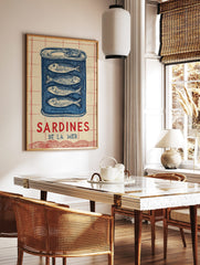 Illustrative blue sardine tin wall art with four fish and 'SARDINES DE LA MER' text on a cream and, in a styled room mockup
