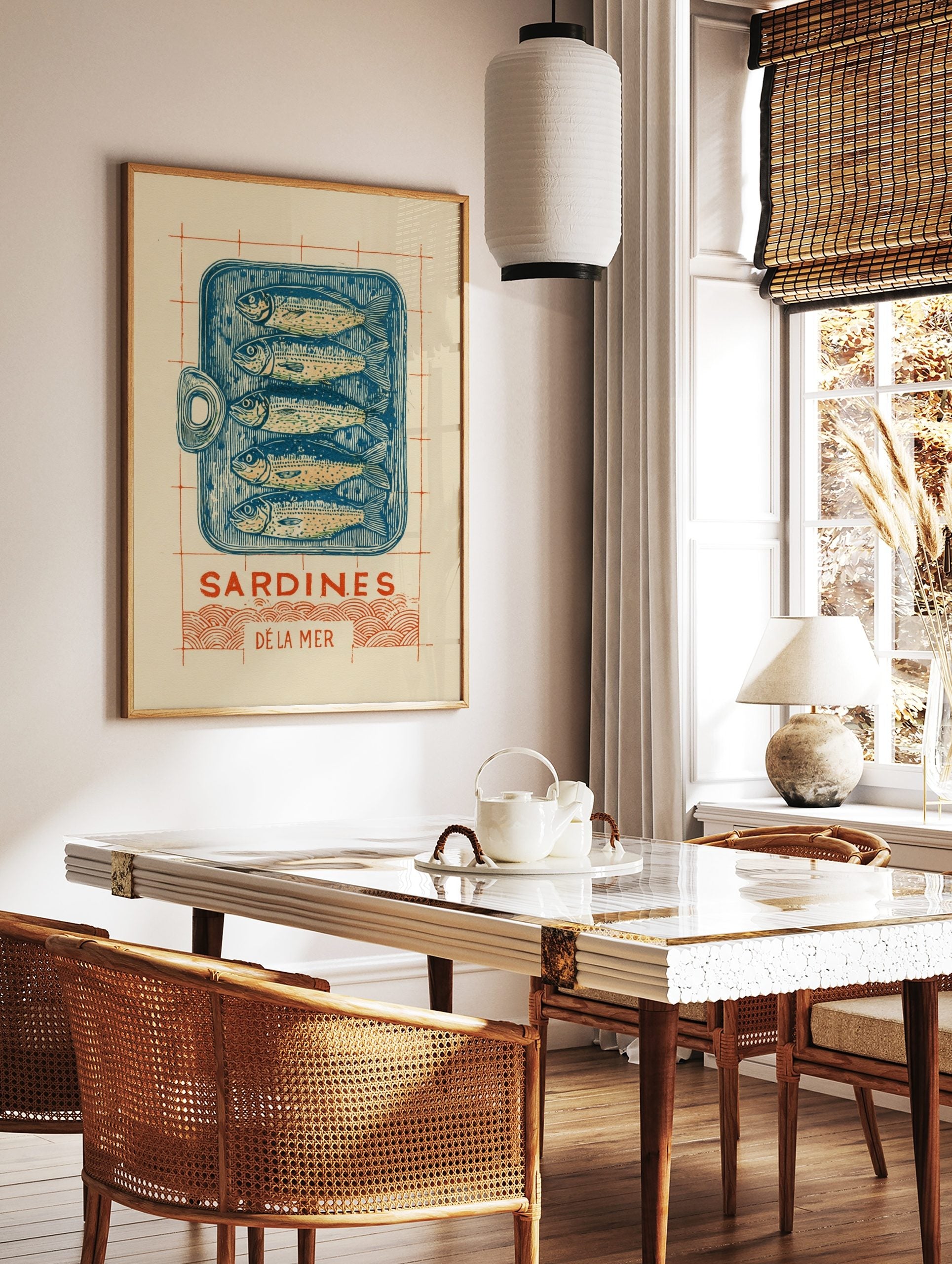 Illustrative linocut-style print of a blue sardine tin with five fish, 'Sardines Dé La Mer' text, in a styled room mockup