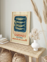 Vintage Sardines De La Mer wall art print with four fish in a blue tin, red grid background, in an alternate framed mockup