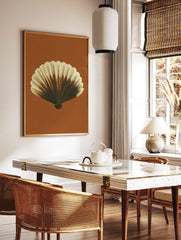 Detailed illustrative print of a scallop shell in brown and cream tones against a rust background, in a styled room mockup
