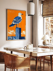 Seagull Wall Art linocut print featuring a blue and white seagull on a dark blue wooden post against an orange sky and ocean. - Image 3