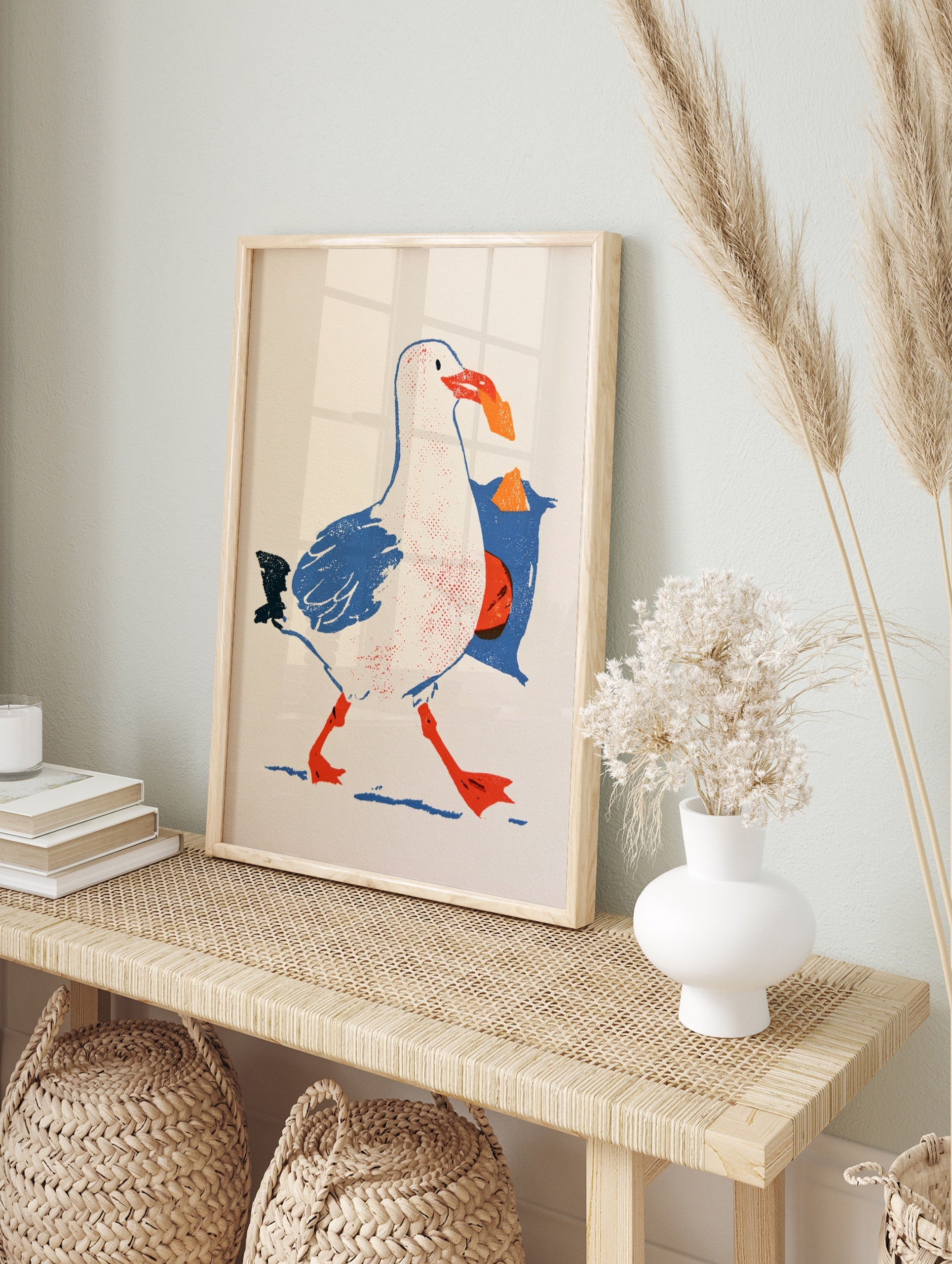 Illustrative seagull art print walking with a blue bag of crisps in its beak on a white, in an alternate framed mockup