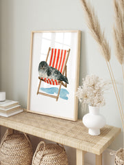 Watercolour illustration of a grey spotted seal sleeping in a red and white striped deck, in an alternate framed mockup