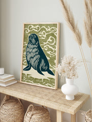 Linocut style seal looking up, dark navy with white details, against an olive green wavy, in an alternate framed mockup