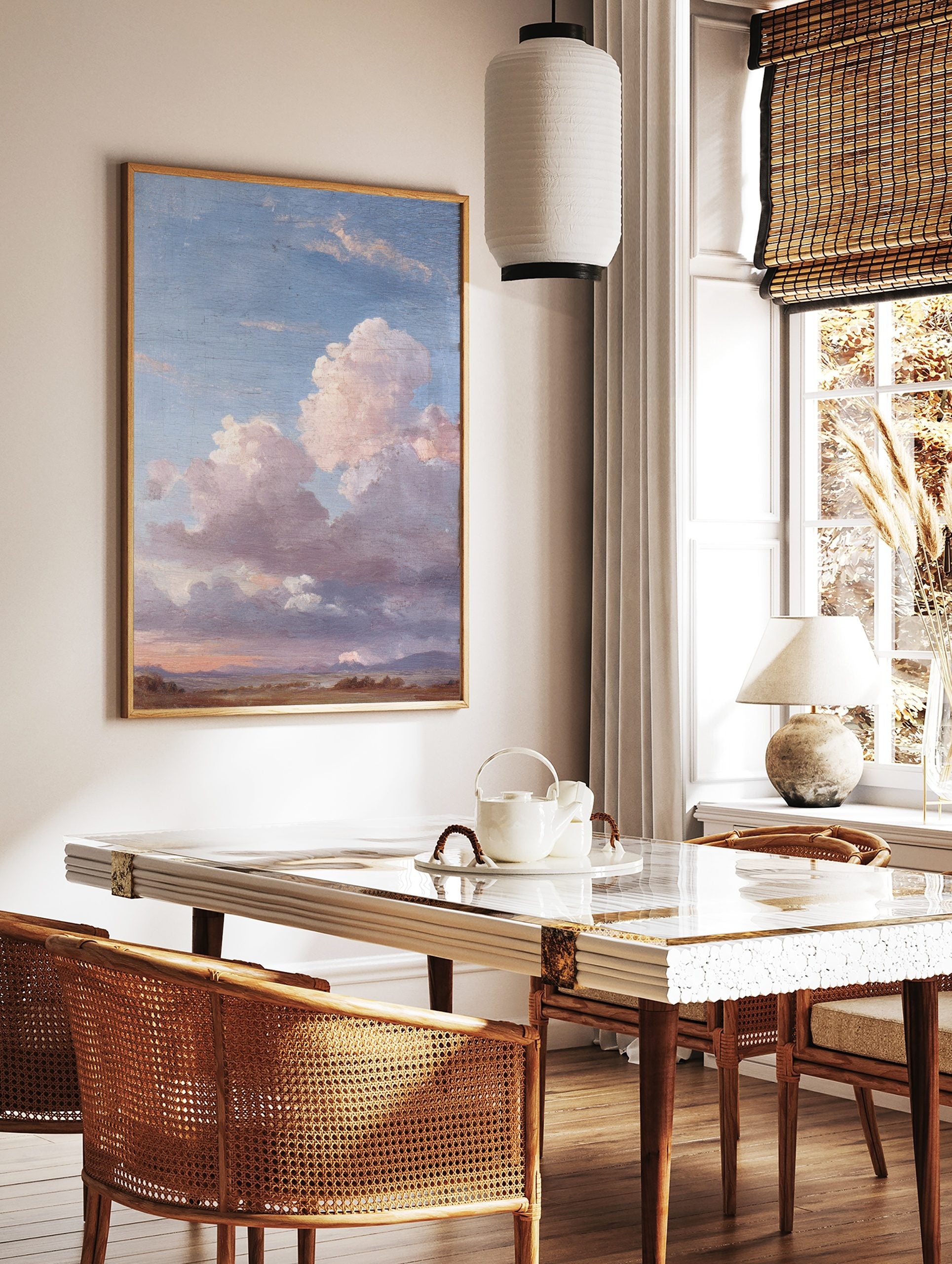 Painterly landscape wall art with vast blue sky, large pink and grey clouds, and earthy fields with, in a styled room mockup