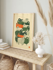Stylised flock of sheep in green, orange, and cream colours, graphic linocut-inspired art, in an alternate framed mockup