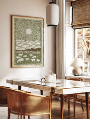 Illustrative green and off-white print of sheep grazing in a field beneath a sun and clouds, with a, in a styled room mockup