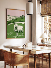 Illustrative print of a white sheep in a green field with rolling hills and pink sky, in a simple, in a styled room mockup