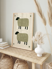Minimalist folk art print featuring two stacked sheep with textured green bodies and black, in an alternate framed mockup
