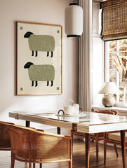 Minimalist folk art print featuring two stacked sheep with textured green bodies and black heads on, in a styled room mockup