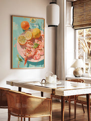Illustrative print of pink shrimp, yellow lemons, and orange fruits on a pink plate against a teal, in a styled room mockup