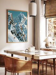 Illustrative mountain wall art print featuring a lone skier in a red jacket on a steep snowy peak, in a styled room mockup