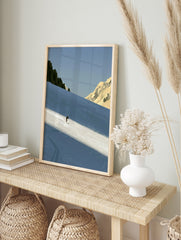 Minimalist skiing mountain wall art featuring a lone skier on a blue snowy slope with rocky, in an alternate framed mockup