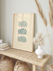 Three stylised sleeping animal shapes with blue floral, checkerboard, and wavy patterns on a, in an alternate framed mockup