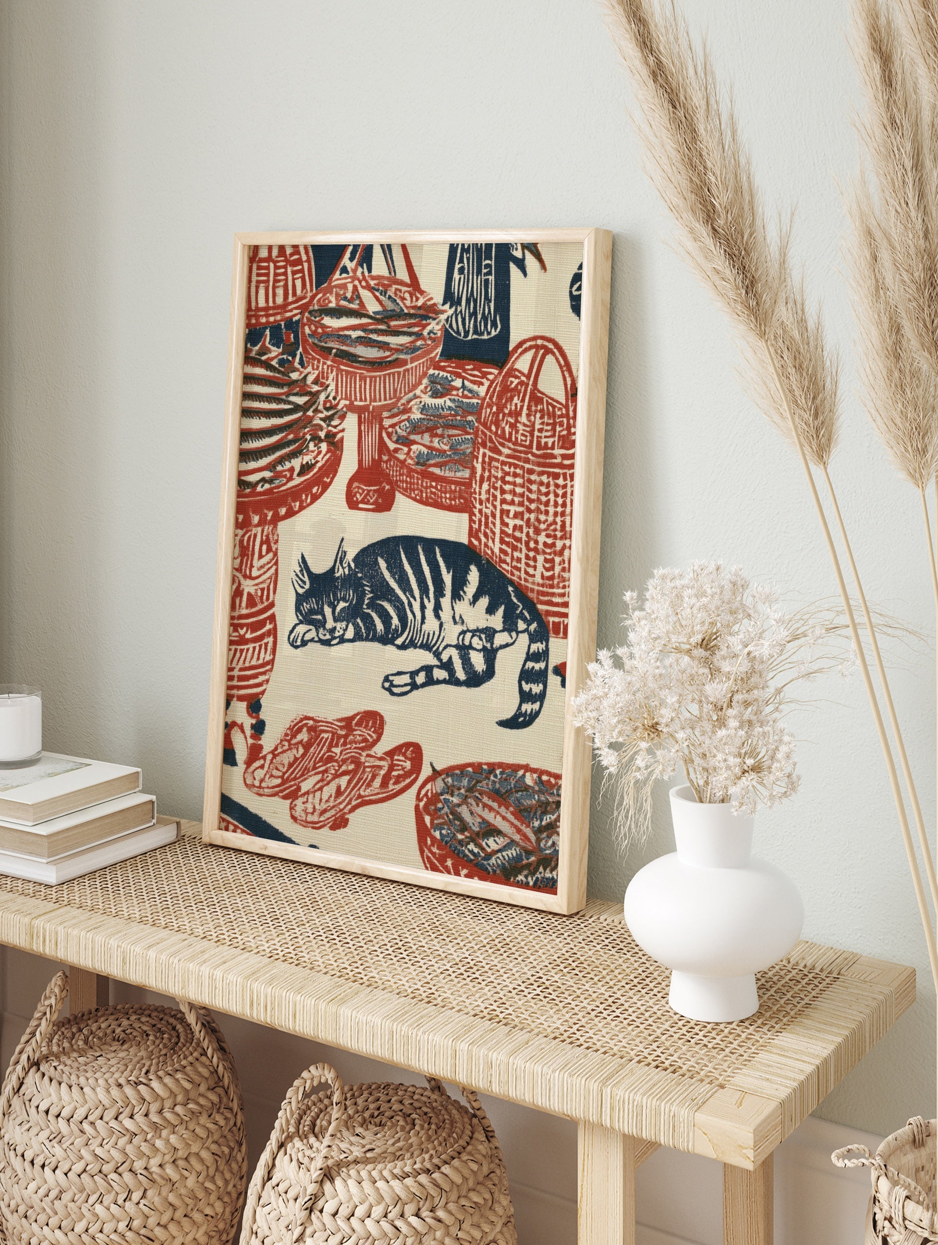 Woodblock style print featuring a sleeping cat surrounded by woven baskets of fish in red and, in an alternate framed mockup