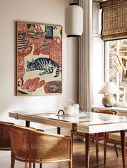 Woodblock style print featuring a sleeping cat surrounded by woven baskets of fish in red and navy, in a styled room mockup
