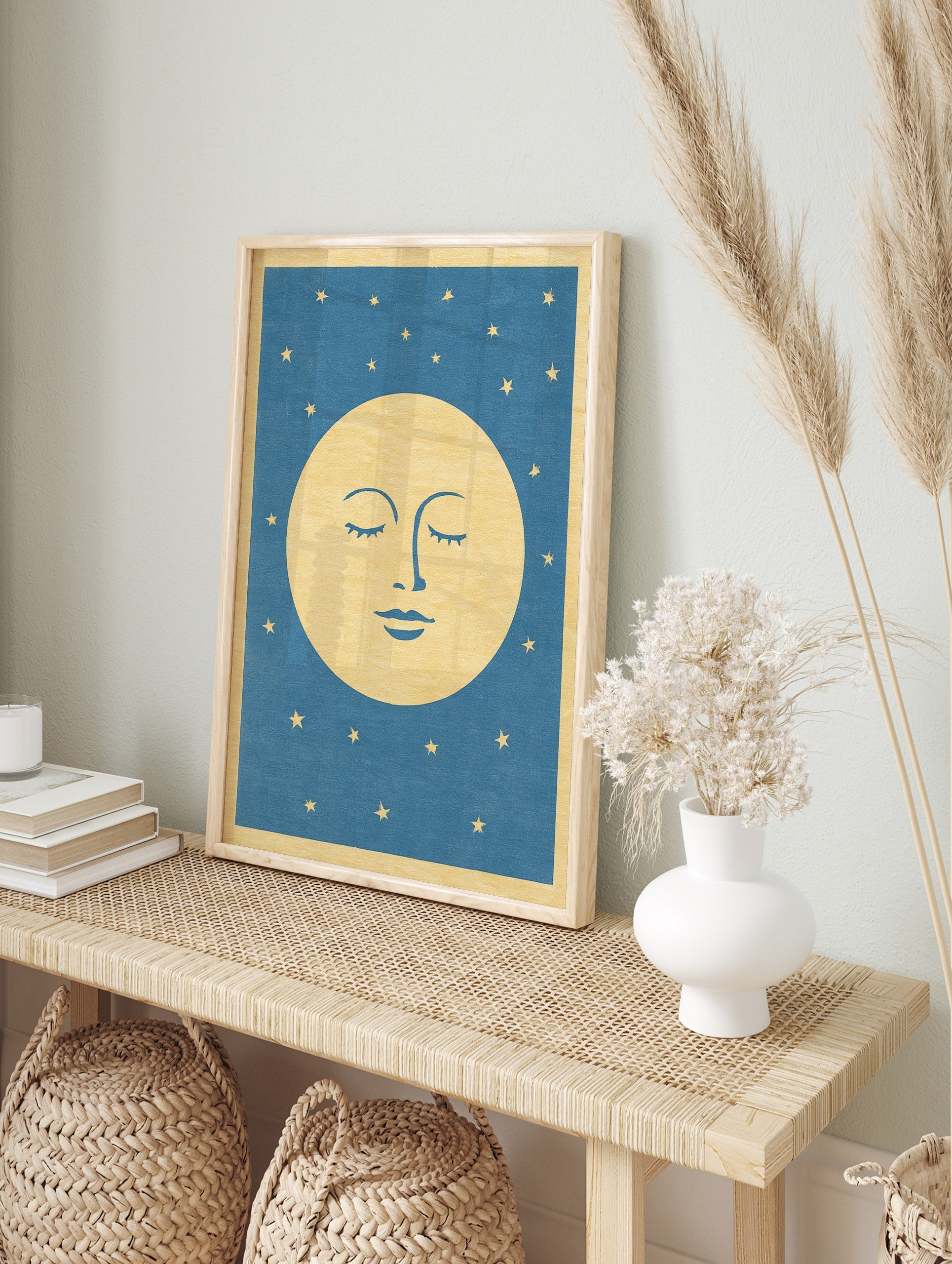 Stylised sleeping moon face illustration with closed eyes and gold stars on a blue, in an alternate framed mockup