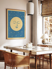 Stylised sleeping moon face illustration with closed eyes and gold stars on a blue background, in a styled room mockup
