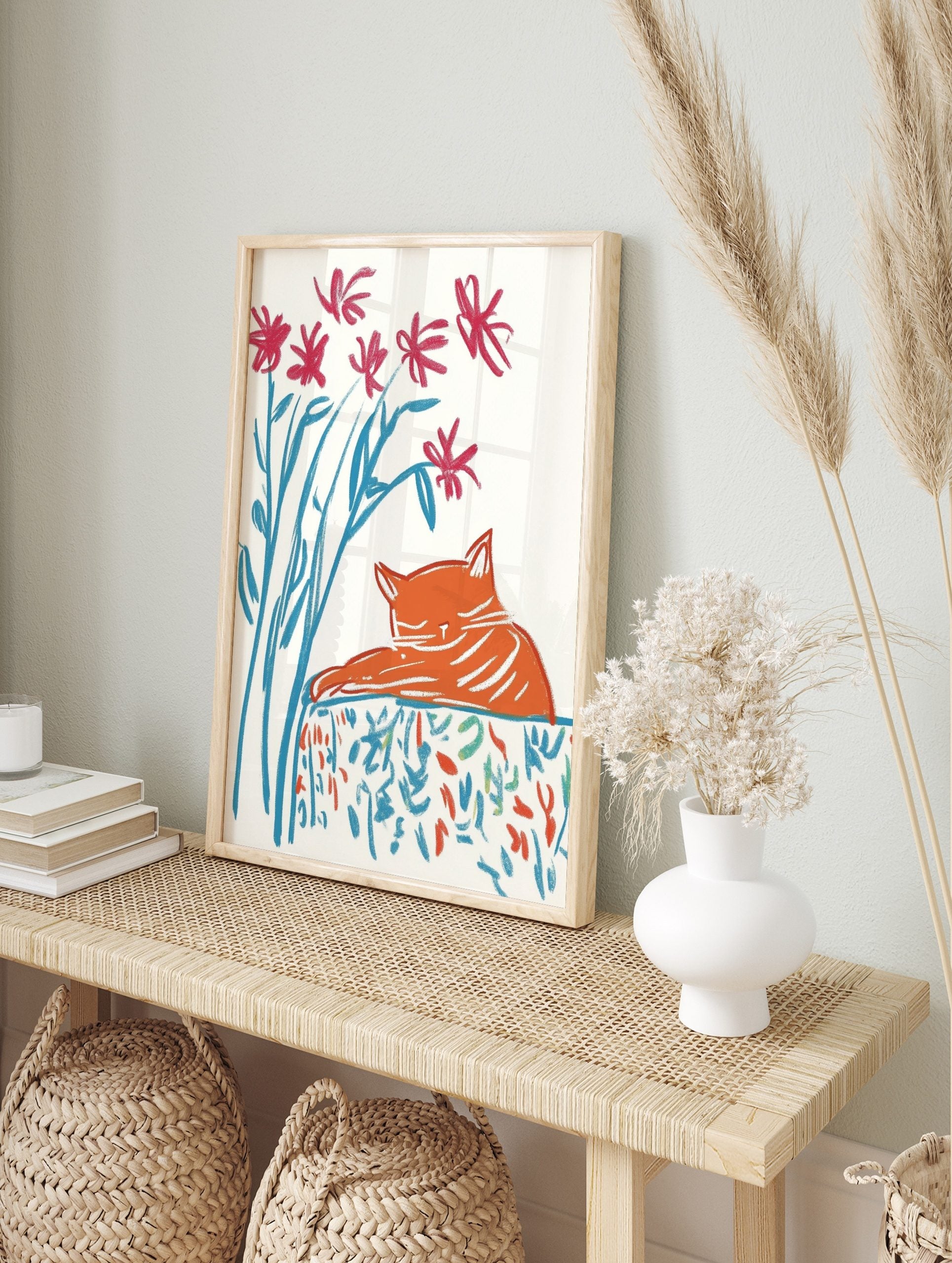 Illustrative print of a sleeping orange cat with red flowers and blue stems on a patterned, in an alternate framed mockup