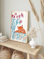 Illustrative print of a sleeping orange cat with red flowers and blue stems on a patterned, in an alternate framed mockup