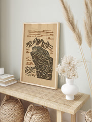 Stylised snow leopard resting on a rocky mountain ledge with peaks and clouds in a two-tone, in an alternate framed mockup