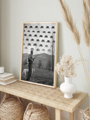 Monochrome print of a man with a rifle and dog looking at pixelated Space Invaders in the sky, in an alternate framed mockup