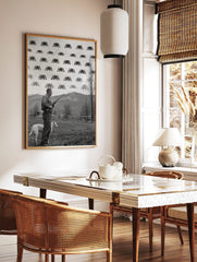 Monochrome print of a man with a rifle and dog looking at pixelated Space Invaders in the sky, in a styled room mockup
