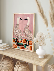 Illustrative wall art of two speckled white ducks facing each other at a dining table with a, in an alternate framed mockup