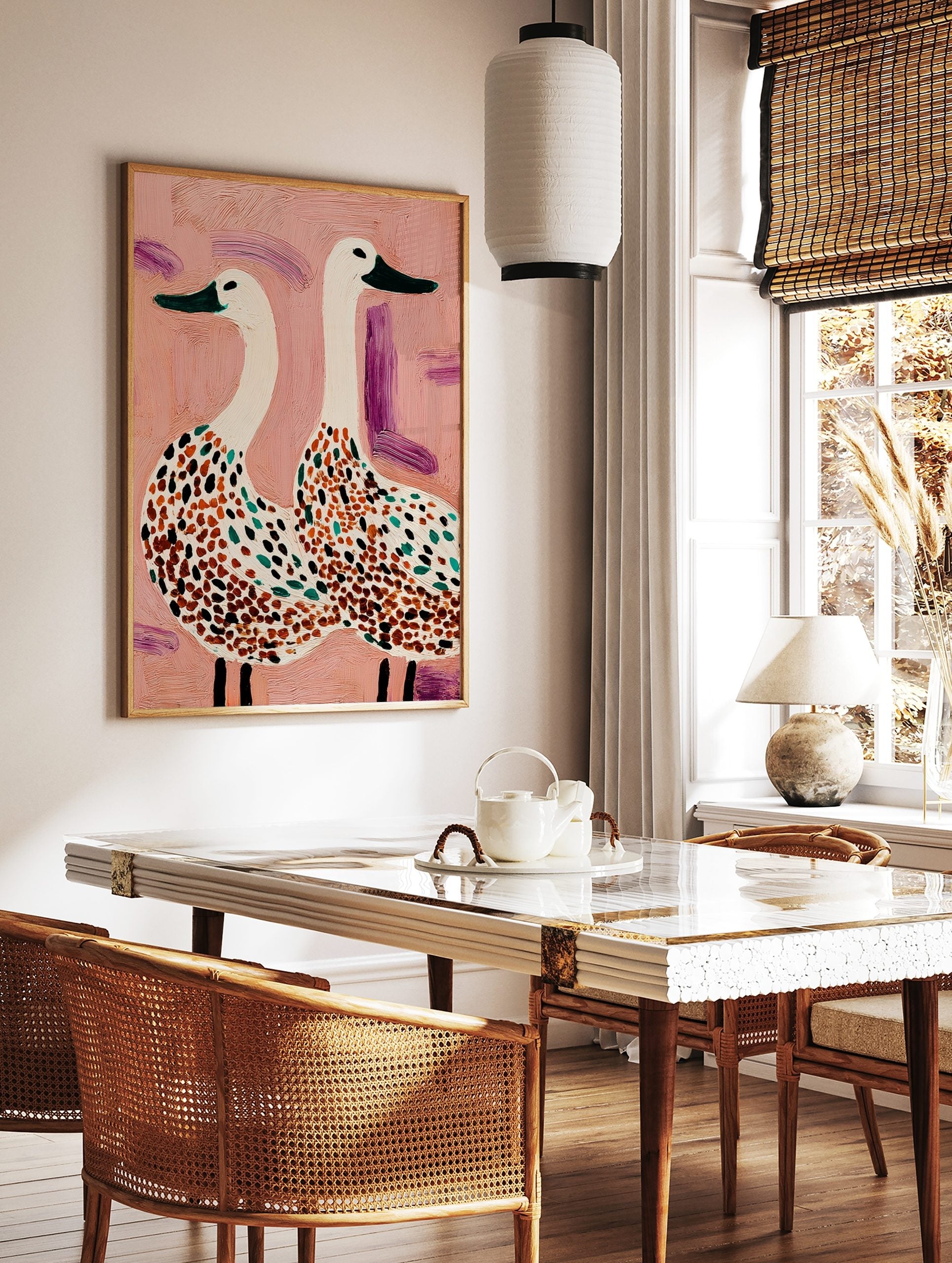 Illustrative wall art of two white spotted geese with green beaks on a textured pink background, in a styled room mockup