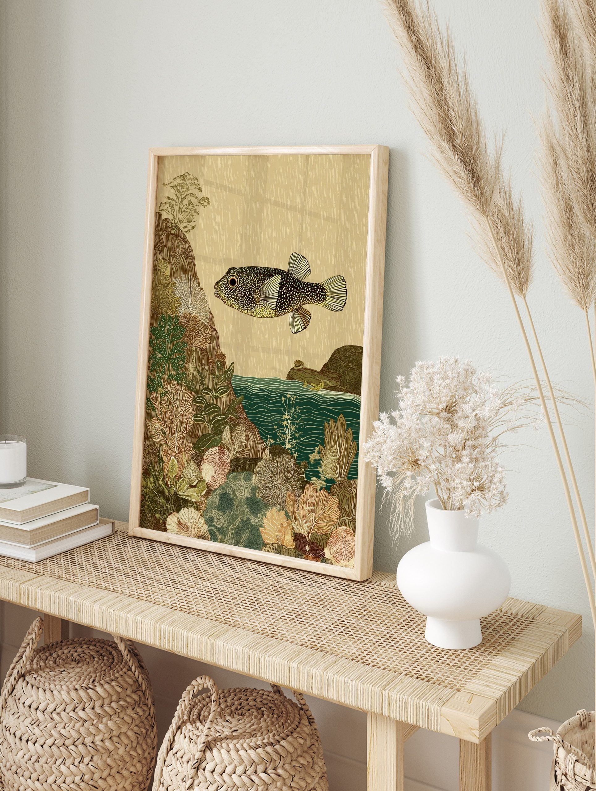 Illustrative art print of a spotted pufferfish swimming over detailed coral and rocky seabed, in an alternate framed mockup