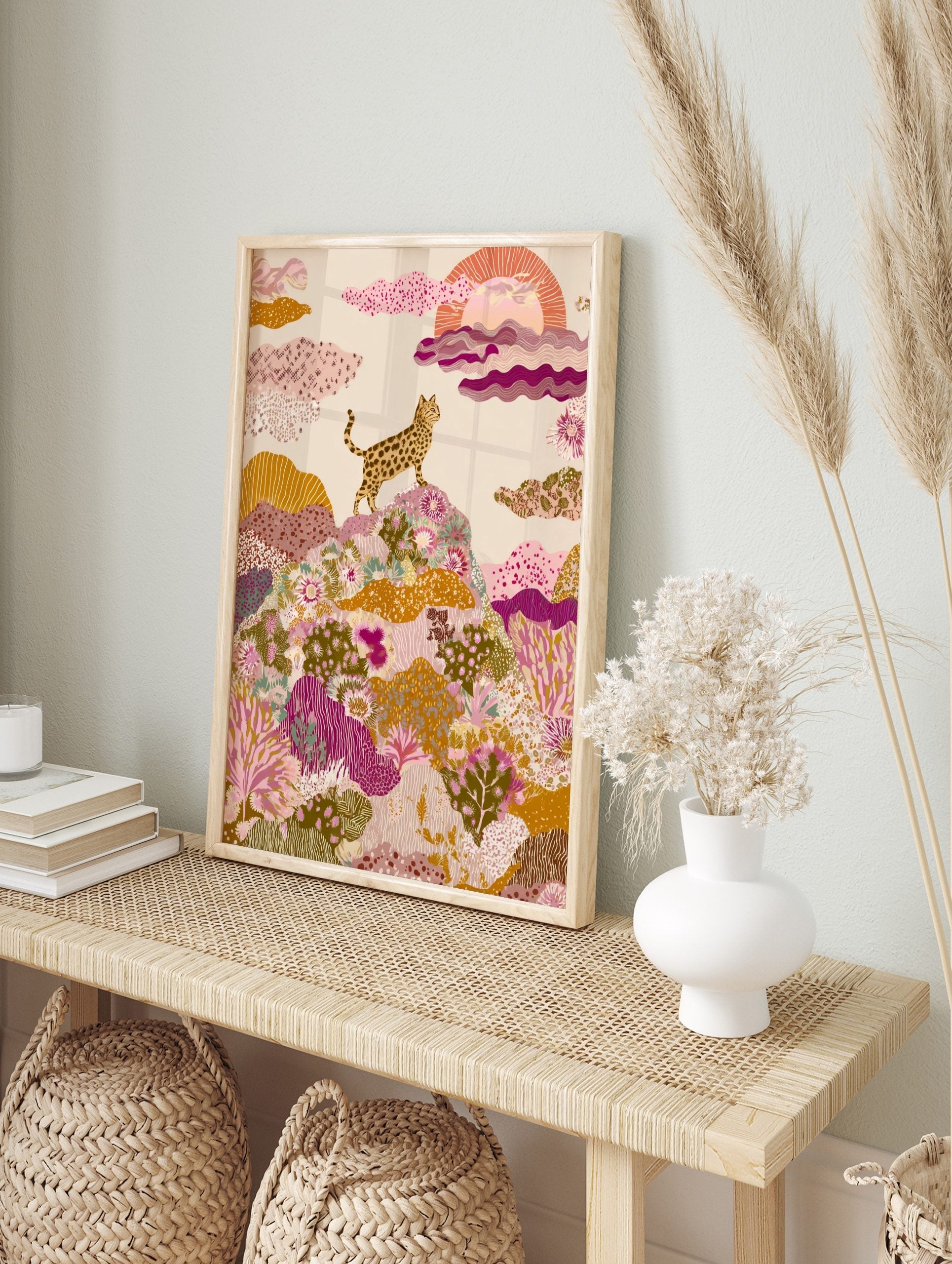 Spotted wild cat on a hill with colourful patterned plants and stylized sun, illustrative art, in an alternate framed mockup