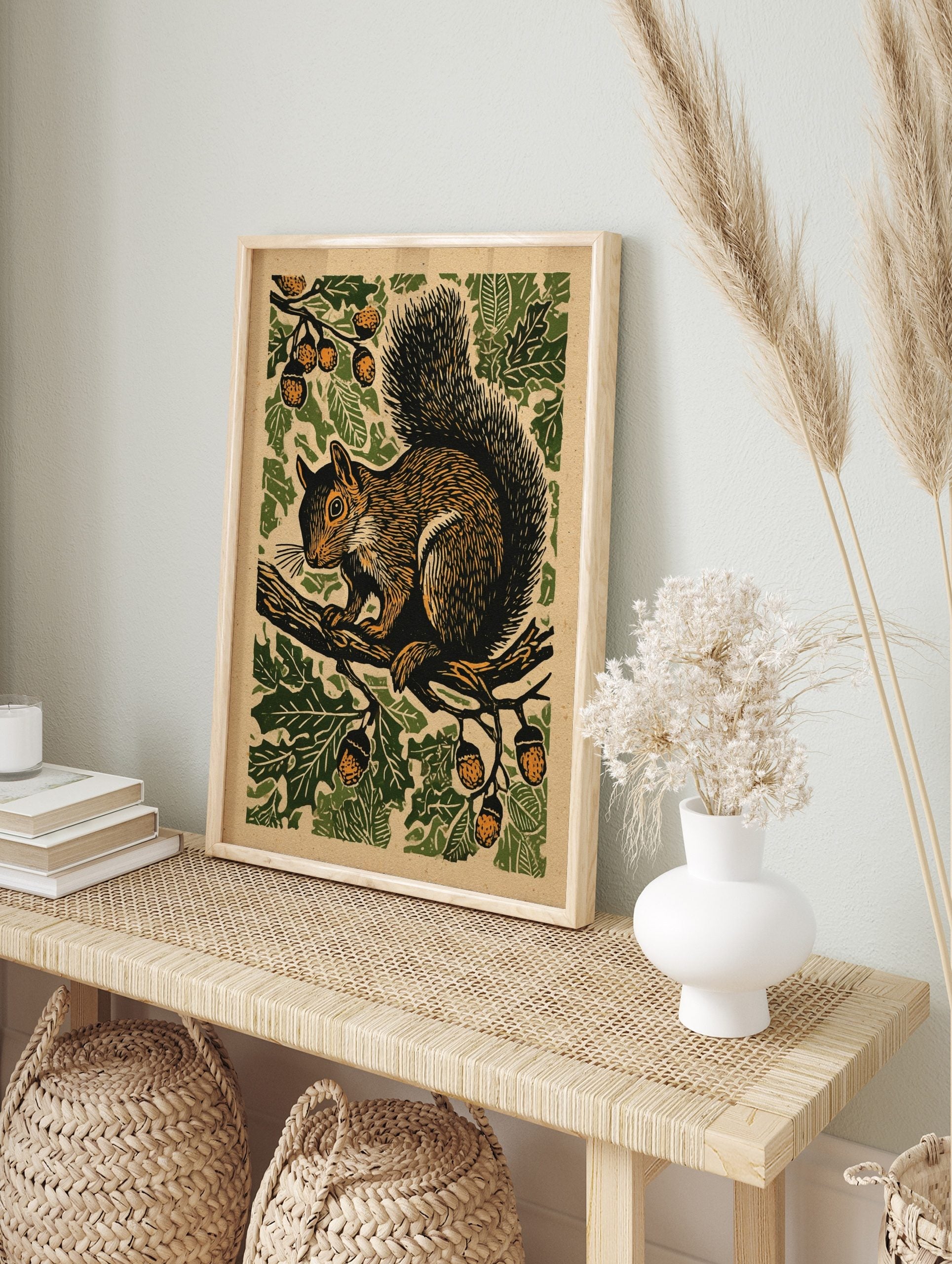 Illustrative woodcut-style print of a brown squirrel on an oak branch with green leaves and, in an alternate framed mockup