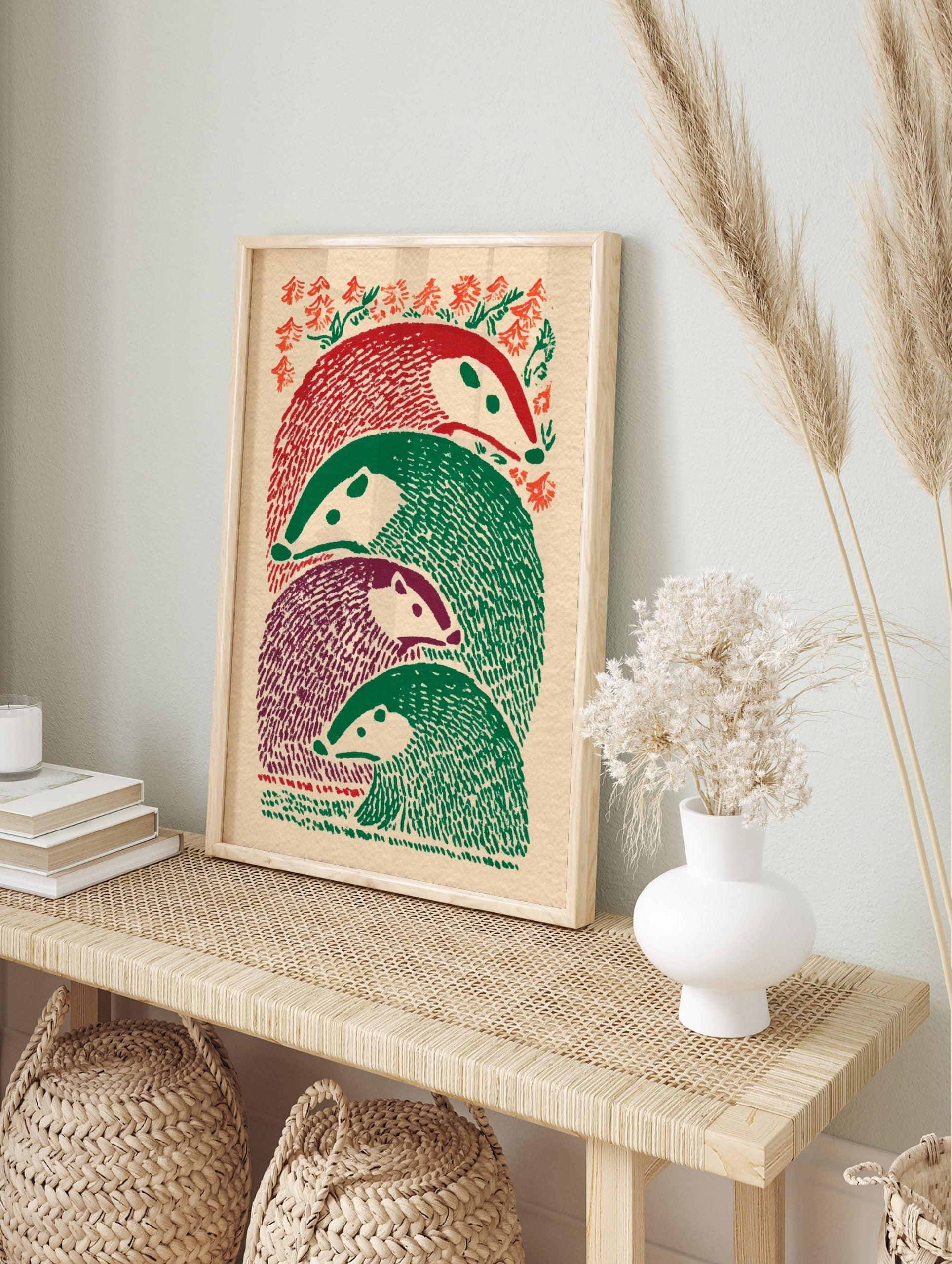 Illustrative print of four stacked badger-like animals in red, green, and purple, with foliage, in an alternate framed mockup