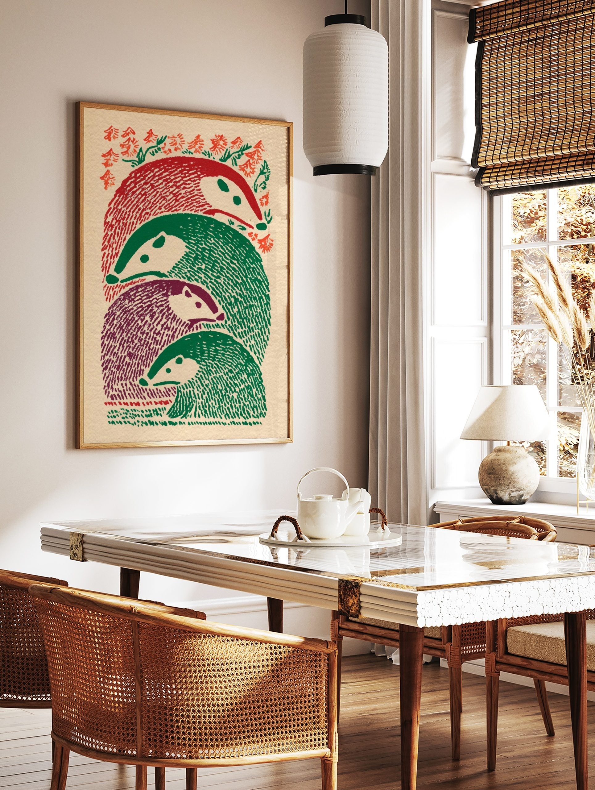 Illustrative print of four stacked badger-like animals in red, green, and purple, with foliage, in a styled room mockup