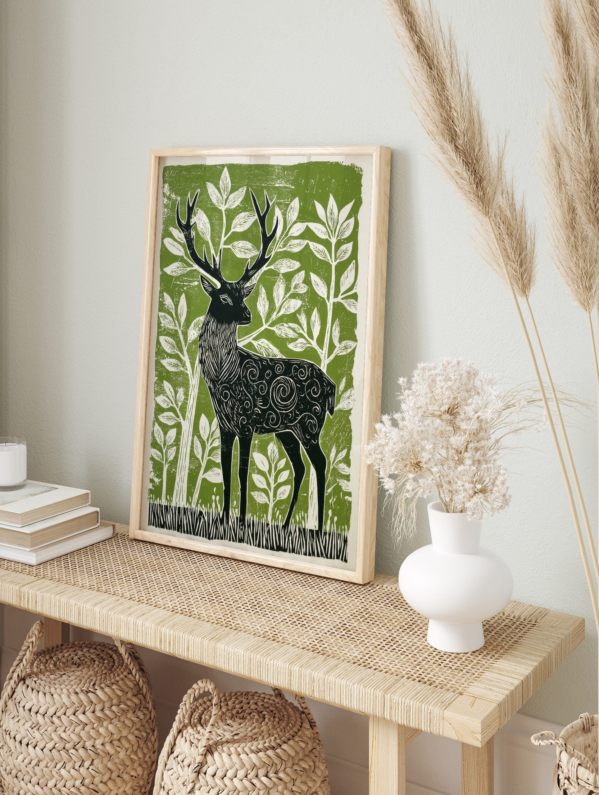 Stylised linocut print of a black stag with ornate patterns, surrounded by white foliage on a, in an alternate framed mockup