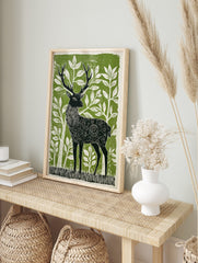 Stylised linocut print of a black stag with ornate patterns, surrounded by white foliage on a, in an alternate framed mockup