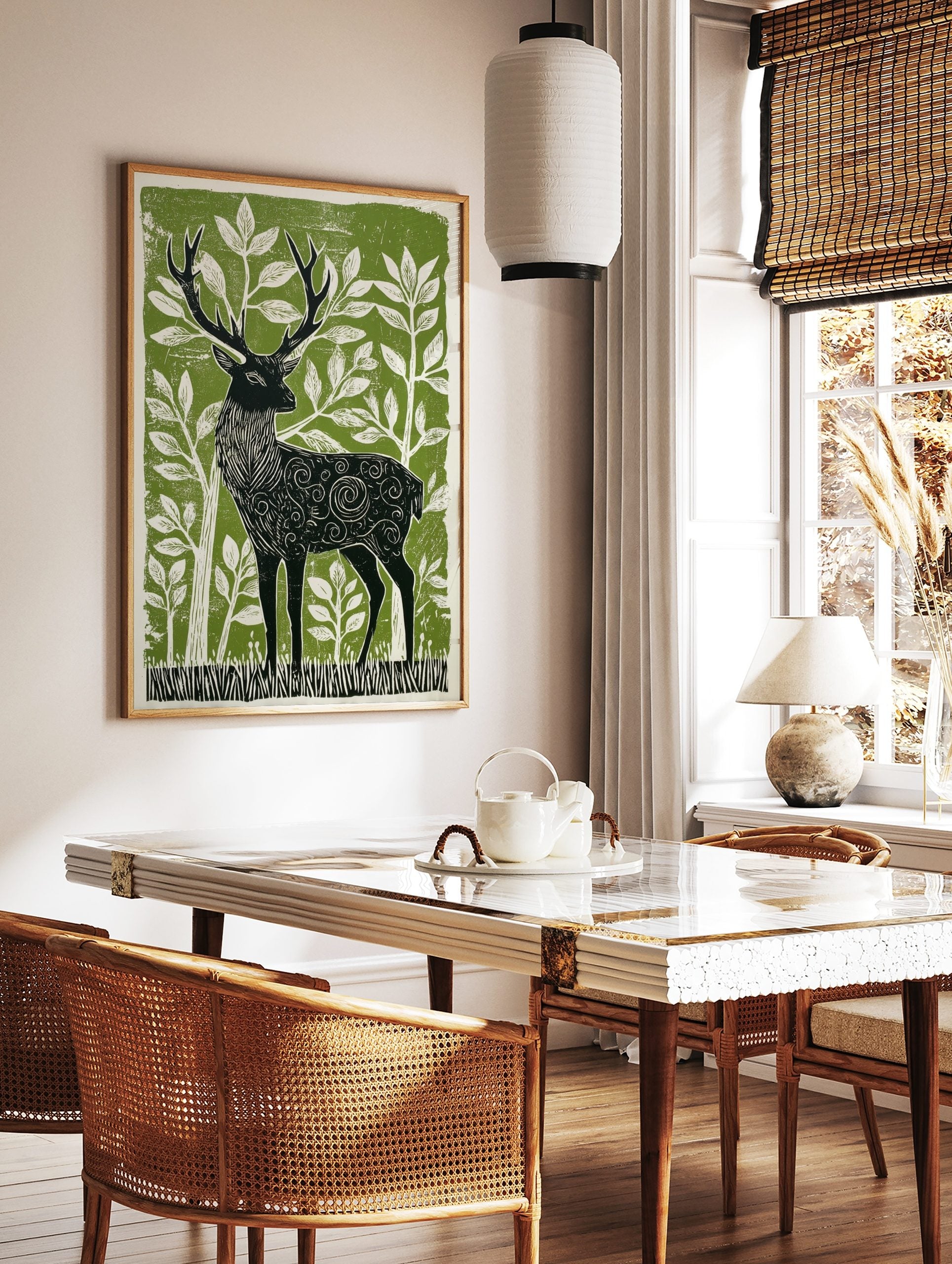 Stylised linocut print of a black stag with ornate patterns, surrounded by white foliage on a green, in a styled room mockup