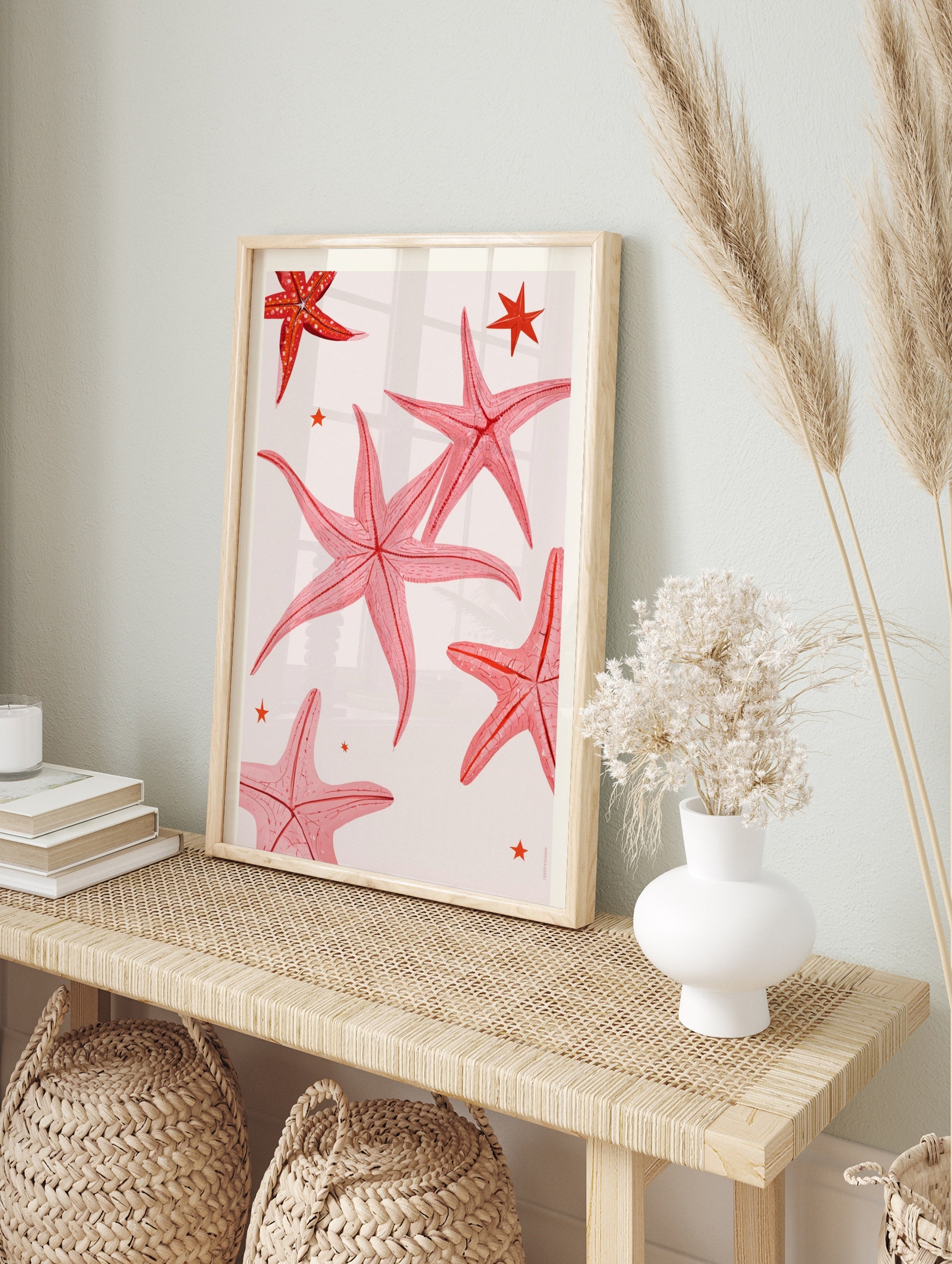 Pink starfish illustration art print with small stars on a neutral background, in an alternate framed mockup