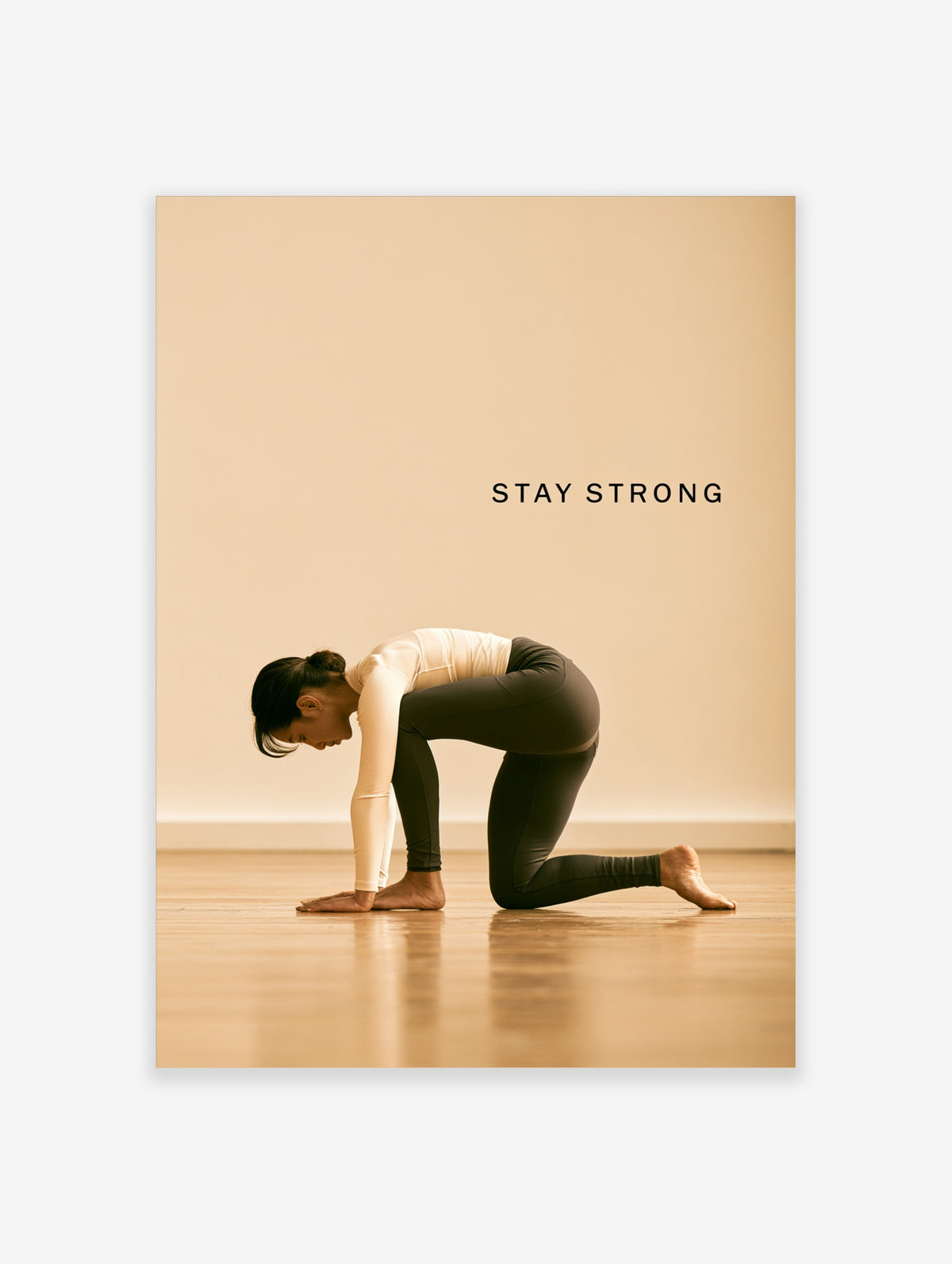 Woman in kneeling yoga pose on wooden floor with STAY STRONG text on beige background