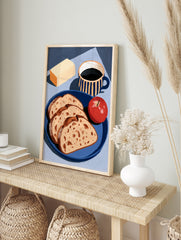 Still life art print of bread slices, an apple, butter, and a striped coffee mug on a blue, in an alternate framed mockup