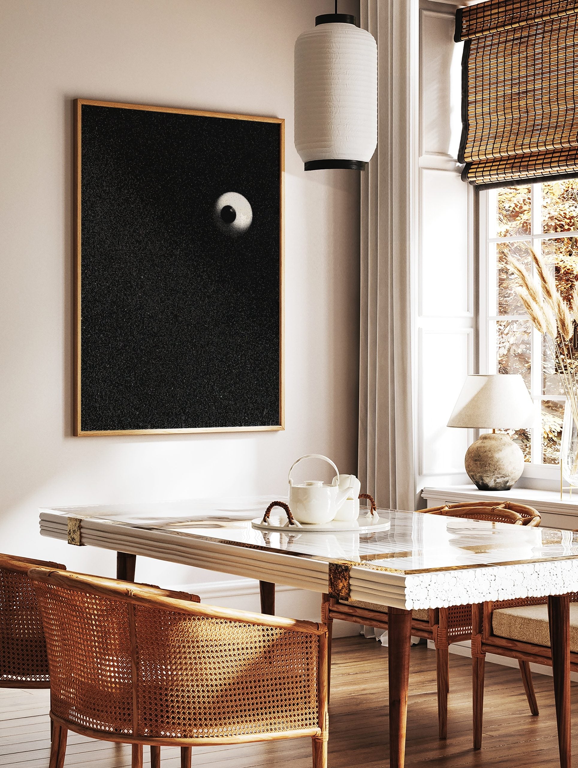 Stippled eyeball art print with a black pupil and light sclera on a speckled black background, in a styled room mockup