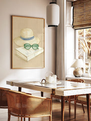 Sketch illustration of a straw hat with blue ribbon, green sunglasses, and a book on a beige, in a styled room mockup