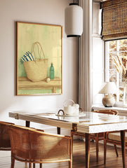 Illustrative print of a straw market bag with a striped towel, green bottle, and spool on a wooden, in a styled room mockup