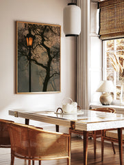 Street lamp at night with glowing light and dark tree branches against a muted sky, in a styled room mockup