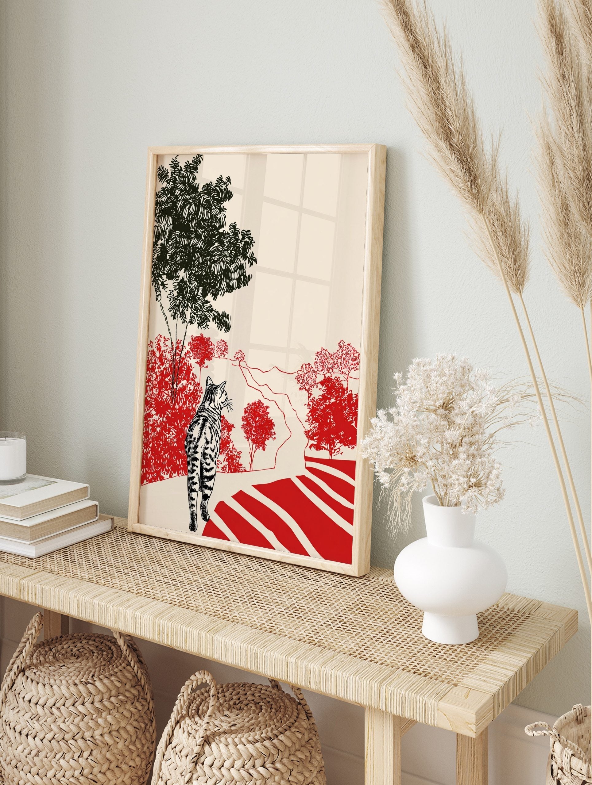 Striped tabby cat walking on a red-striped path through red bushes and green trees, in an alternate framed mockup