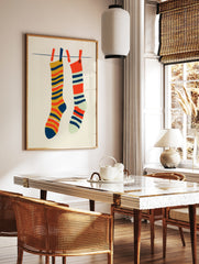Illustrative art print of two striped socks hanging on a laundry line against a cream background, in a styled room mockup