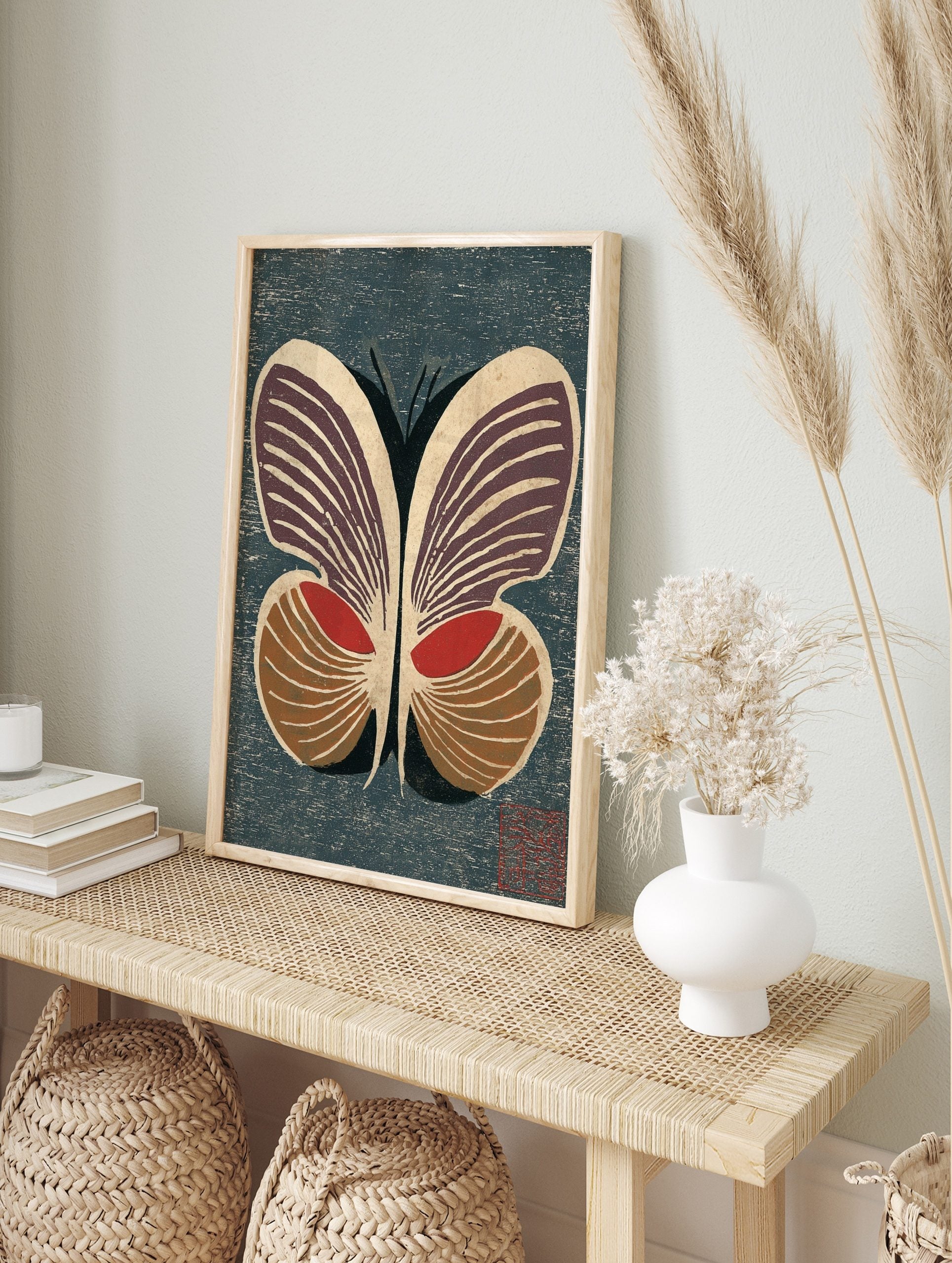 Stylised butterfly woodblock print with deep purple, red, and brown wings on a textured dark, in an alternate framed mockup
